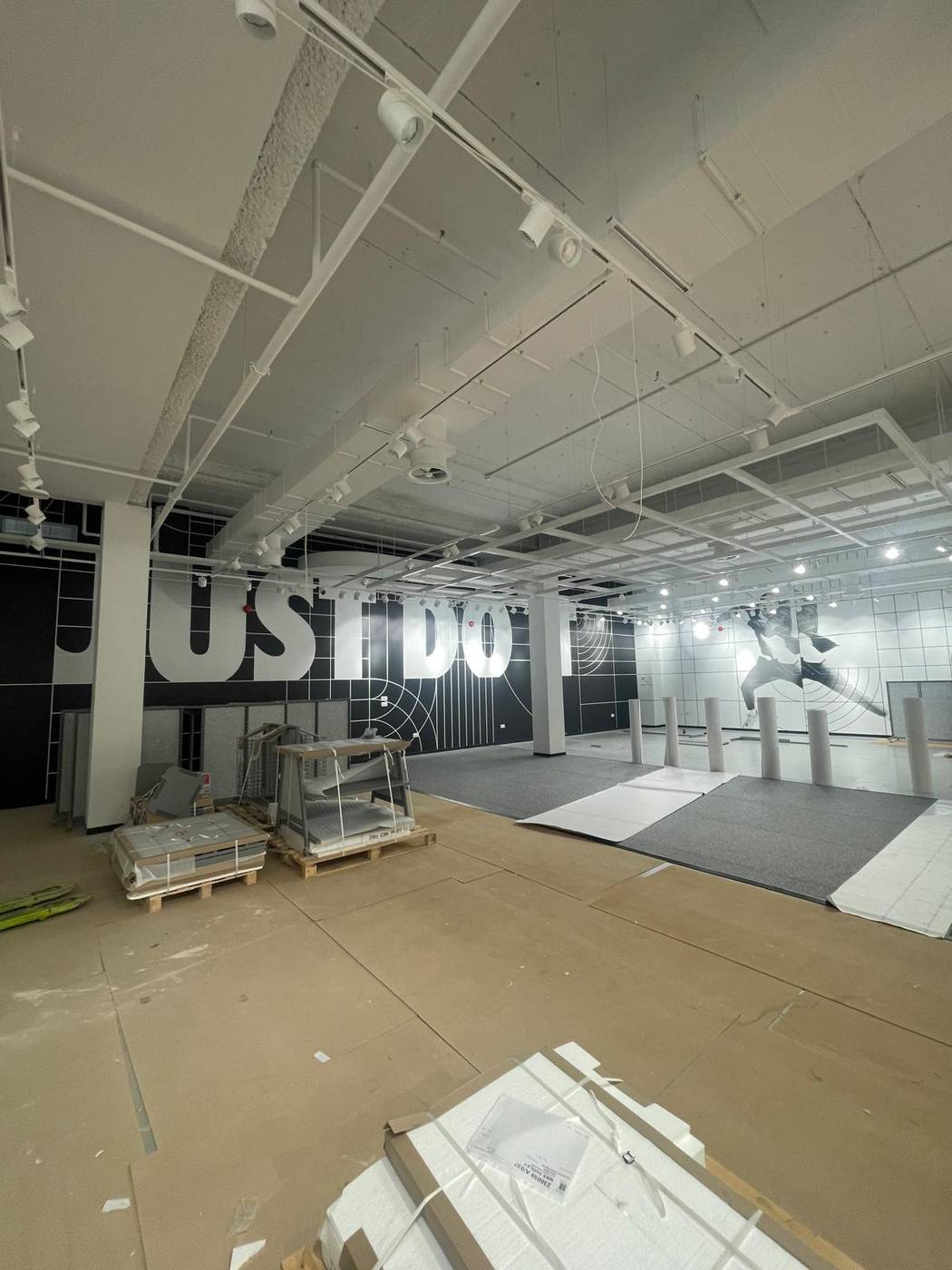 Retail store fit-out in progress with exposed ceiling grid and branding wall
