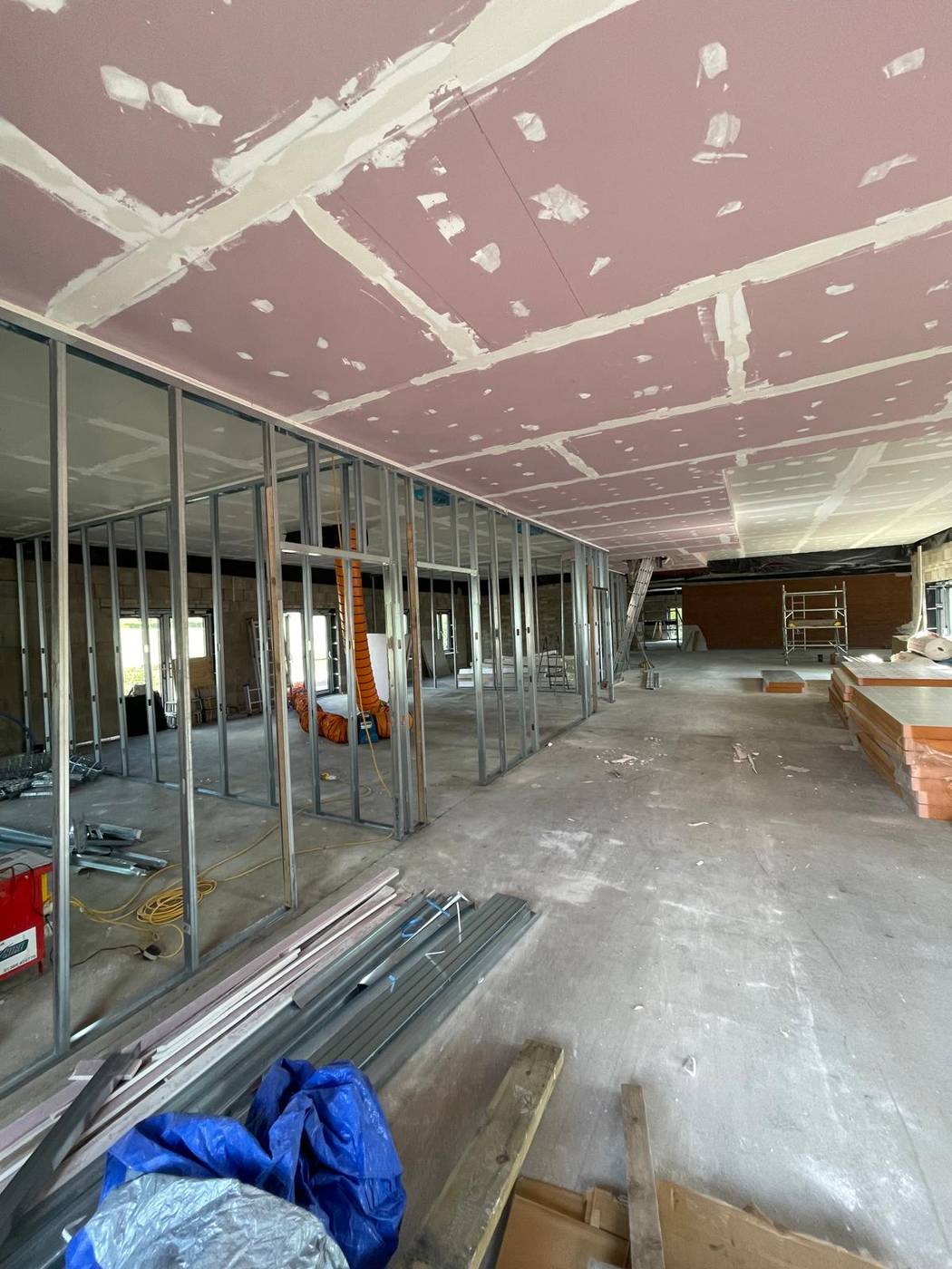 Open commercial space with boarded ceiling and metal stud partitions